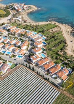 Drone aerial of holiday village with luxury houses at an idyllic rocky coast. Summer vacations at the sea. Protaras Cyprus